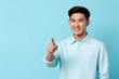 Cheerful smiling asian young man with braces in blue shirt, pointing fingers upper right corner