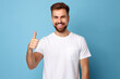 © Uzair - Portrait of cheerful man smiling and showing thumb up over blue background
