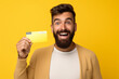 © Uzair - financial services concept positive brunet adult man holds credit card uses electronic money