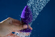 © Михаил Решетников - Woman washing purple anal plug under shower on blue background.