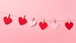Valentine's Day paper hearts hanging on a clothesline on a pink background.