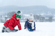 © somemeans - Siblings outside in the snowy day. Two children play and sitting on the snow on frosty winter day. Winter holidays
