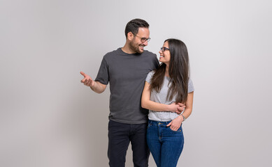 Wall Mural - Romantic man with arm around girlfriend holding hands and looking at each other on white background