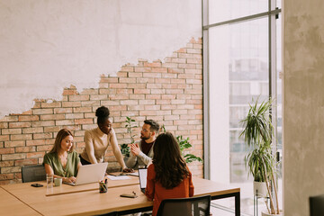 Wall Mural - Young multiethnic startup team working by the brick wall in the industrial style office