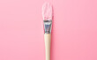 Paintbrush with pink paint on a pink background