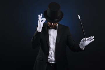 Wall Mural - Magician in top hat holding wand on dark blue background