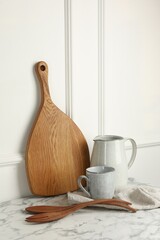 Poster - Wooden cutting board, cutlery and dishware on white marble table