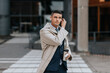 © Maskot - Businessman wearing wireless in-ear headphones while standing at street
