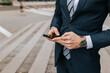© Maskot - Midsection of businessman using smart phone standing at street