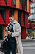 © Maskot - Happy businessman using smart phone while standing at street