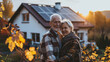 Smiling elderly couple standing in front of their home in the evening