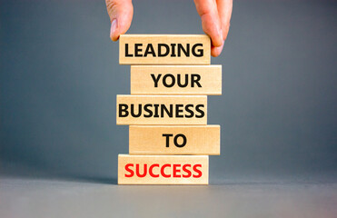 Wall Mural - Leading your business to success symbol. Concept words Leading your business to success on wooden blocks. Beautiful grey table grey background. Leading your business to success concept. Copy space.