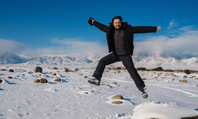 Sticker - Young happy man jumping on mountains background in winter