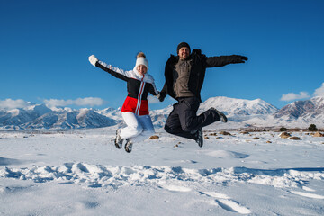 Canvas Print - Happy young couple jumping on mountains background in winter season