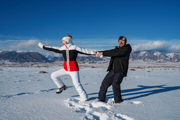 Wall Mural - Happy young couple having fun on mountains background in winter season