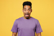 Young mad sad angry shocked man of African American ethnicity he wears purple t-shirt casual clothes looking camera scream shout isolated on plain yellow background studio portrait. Lifestyle concept.