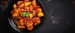 Indo-Chinese Honey Chilli Potatoes in black bowl on dark slate table top, viewed from above with space for text.