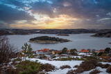 Fototapeta  - View over a stony coastal landscape in winter. Snow, ice and withered heather. Landscape shot in the town of Fjällbacka on the west coast of Sweden