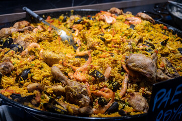 Street food in France, fresh prepared colorful paella with rice and sea food in big pan on street market ready to eat