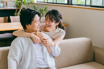 Poster - 家のリビングにいる仲良しの若い日本人夫婦（スキンシップ）
