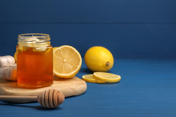 Wall Mural - Honey with garlic in glass jar, lemons and dipper on blue wooden table. Space for text