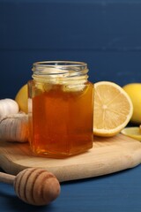 Wall Mural - Honey with garlic in glass jar, lemons and dipper on blue wooden table