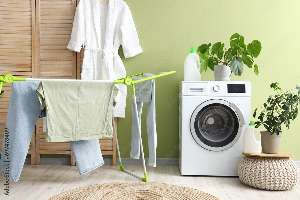 Laundry room interior with washing machine and clothes on drying rack
