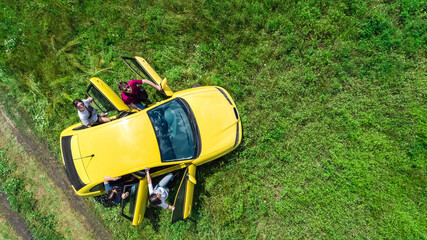 Wall Mural - Family and friends car travel on vacation, happy parents and kids have fun in holiday trip, aerial drone view of car and people from above
