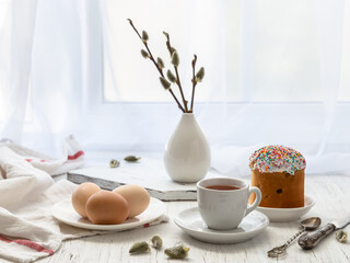 Wall Mural - Easter still life with painted eggs, Easter cake and tea in a cup on the windowsill on a sunny day.