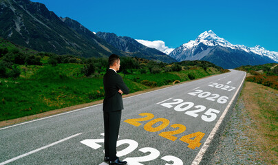 Wall Mural - 2024 New Year journey and future vision concept . Businessman traveling on highway road leading forward to happy new year celebration in beginning of 2024 for bliss and successful start .