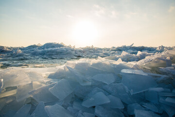 Large pieces of ice near the river bank at sunset