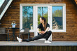 © boomeart - Active woman stretching her arms and legs on terrace of her log cabin