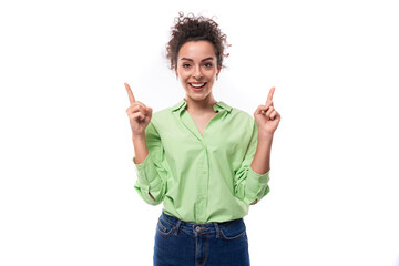 Wall Mural - young positive cheerful slender european brunette curly woman with a ponytail hairstyle is dressed in a green shirt smiling on a white background with copy space