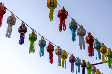 A view from below of colorful lantern flags hanging on strings of lights.