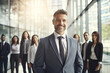 © Kitta Studio - Portrait of confident mature businessman standing in front of his business team