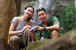 © wattana - Happy young couple sitting by tropical waterfalls. Traveling, freedom and active lifestyle concept.