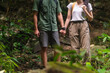© wattana - Young couple on a hiking trip walking along the path of the tropical forest. Travel, vacation and active lifestyle concept.