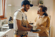© Daria - Beautiful young woman signing document while communicating with handyman at the kitchen