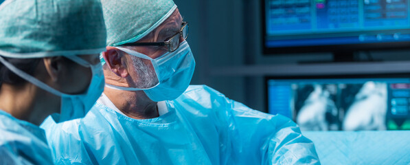 Team of medical doctors performs surgical operation in modern operating room using high-tech technology. Surgeons are working to save the patient in the hospital. Medicine, health and science.