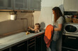 © Ala - baby bathes in the kitchen sink. Mom watches the child.