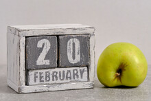 February 20th On Wooden Calendar And Green Apple On White Background. Apple Day USA.