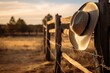 A Symbolic Embrace of the Frontier: A cowboy hat and lasso adorn a wooden fence, embodying the timeless essence of ranch life and the rugged spirit of the Wild West.