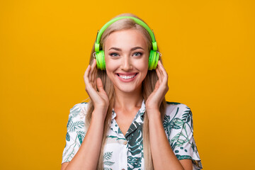 Wall Mural - Photo of good mood gorgeous girl with long hairdo dressed print shirt arms touching headphones isolated on yellow color background