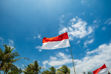 Indonesia flag waving in wind on blue sky background. International relations and tourism concept. 