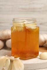 Wall Mural - Honey with garlic in glass jar on board, closeup