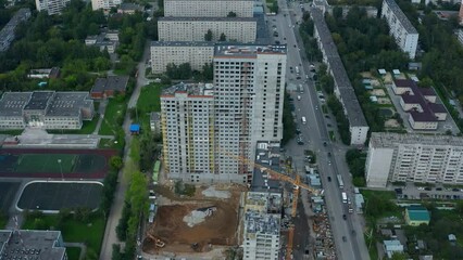 Wall Mural - Top view of city with construction of high-rise building. Stock footage. Construction of multi-storey complex in residential area of modern city. Construction of high-rise building with crane on