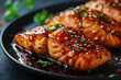 Teriyaki salmon fillet baked in an oven served on a black plate with lime wedges on a concrete table, horizontal view from above. Image for the menu