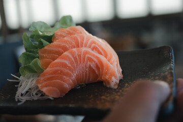 Wall Mural - Raw salmon slice or salmon sashimi in Japanese style fresh. This cuisine will more enjoyable when eating with wasabi, soy sauce, and pickled ginger.