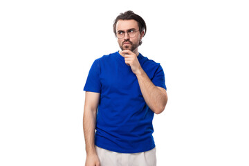 Canvas Print - young smart caucasian man with dark well-groomed hair and a beard in a blue t-shirt on a white background