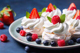 Pavlova meringue mini cakes with whipped cream and fresh berries.